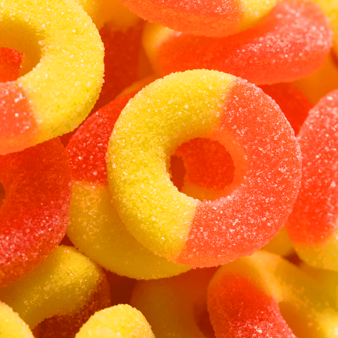 Close-up of Delta 9 Peach Rings, showcasing yellow and red sugar-coated gummy rings stacked and overlapping, evoking the vibrant allure of THCp-infused candies.