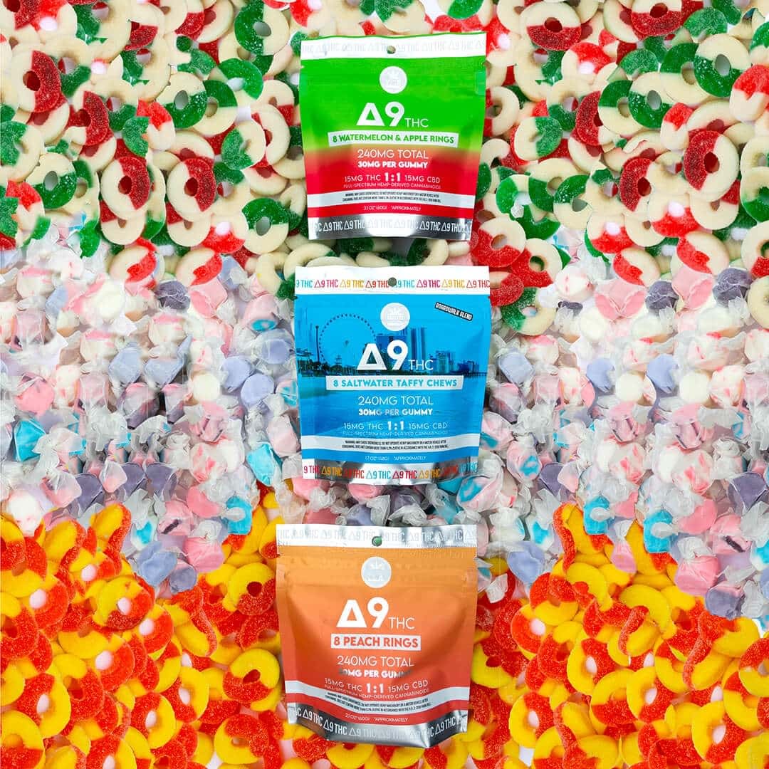Three vibrant bags of THCp edibles in watermelon, saltwater taffy, and peach flavors are artfully arranged on a backdrop of assorted gummy candies.
