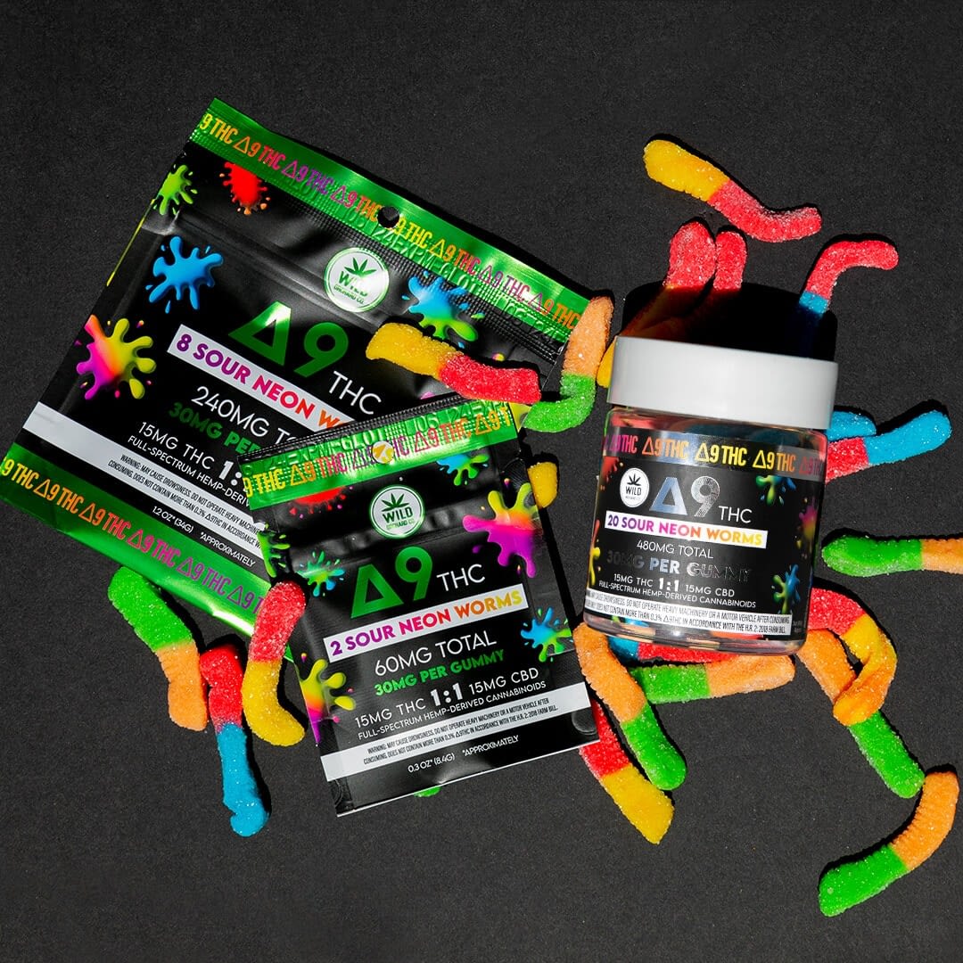Colorful gummy worms and two packages labeled with THCp content are placed on a dark surface, offering a playful twist to classic edibles.